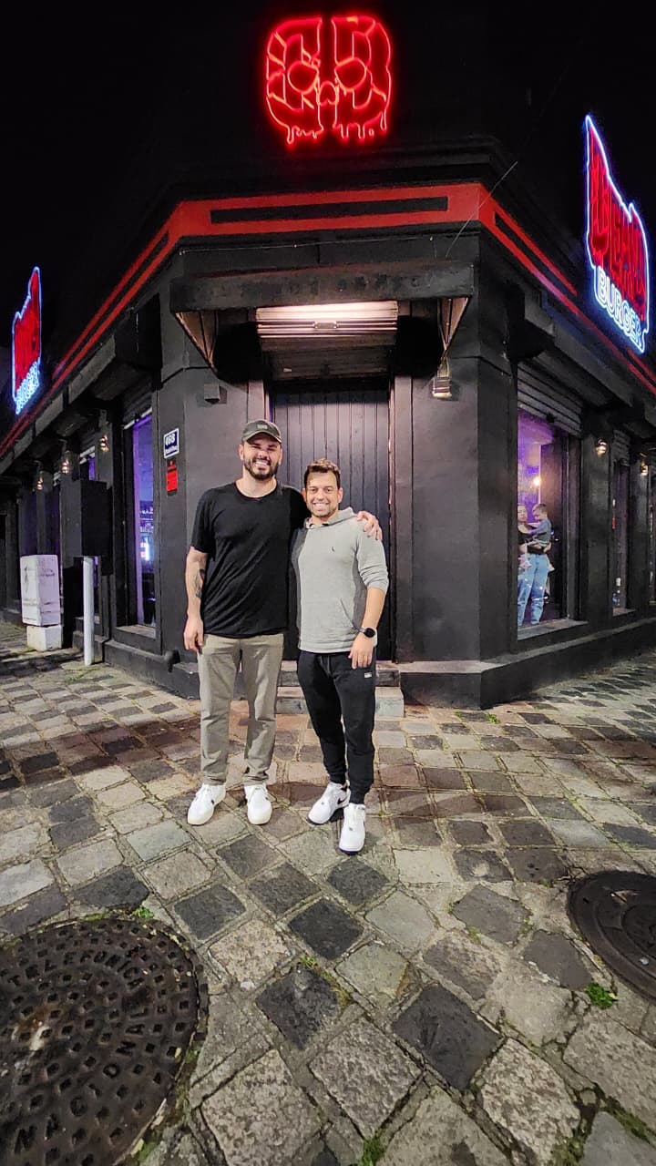 Duas pessoas em frente à fachada da Dead Burger à noite
