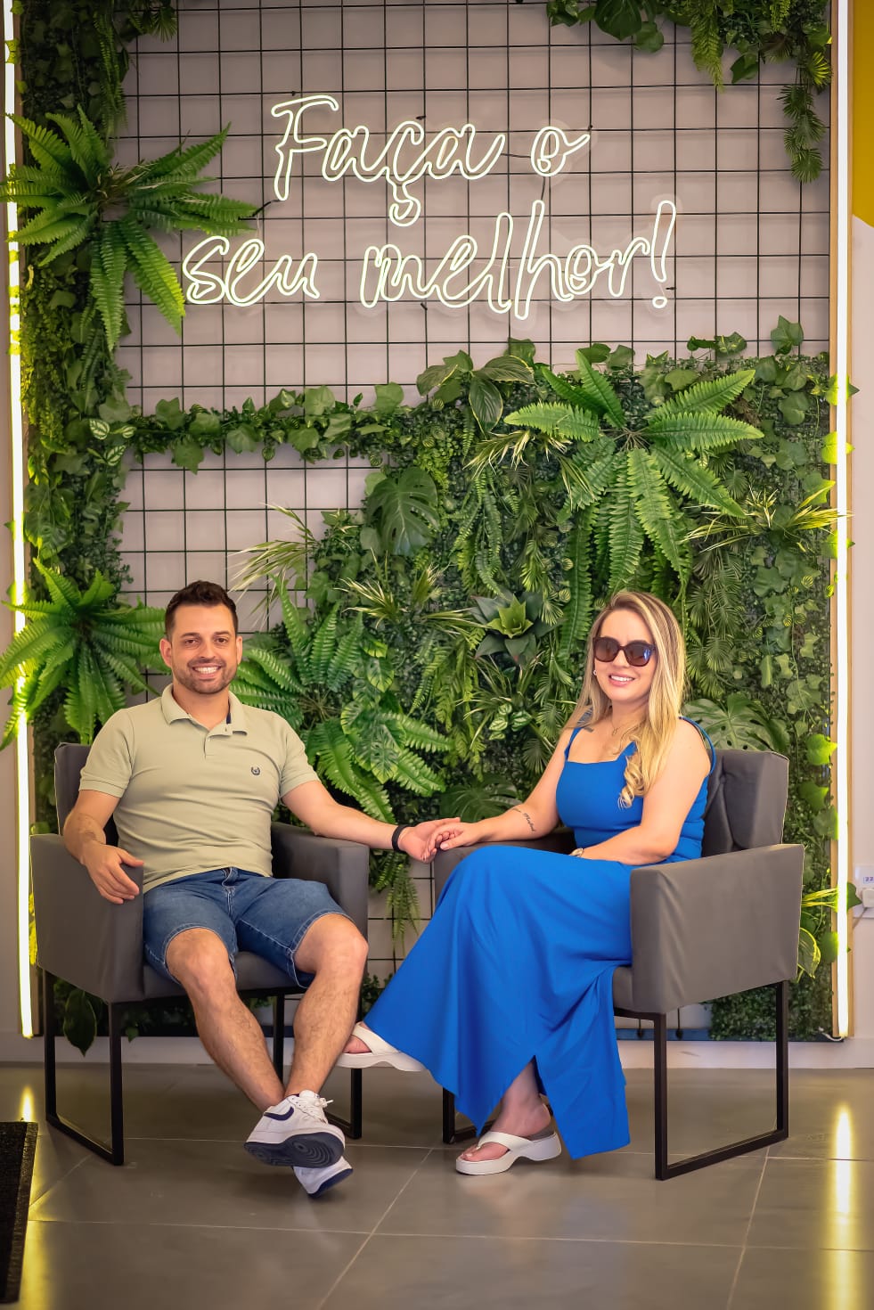 Duas pessoas sentadas diante de um painel verde com a frase Faça o seu melhor